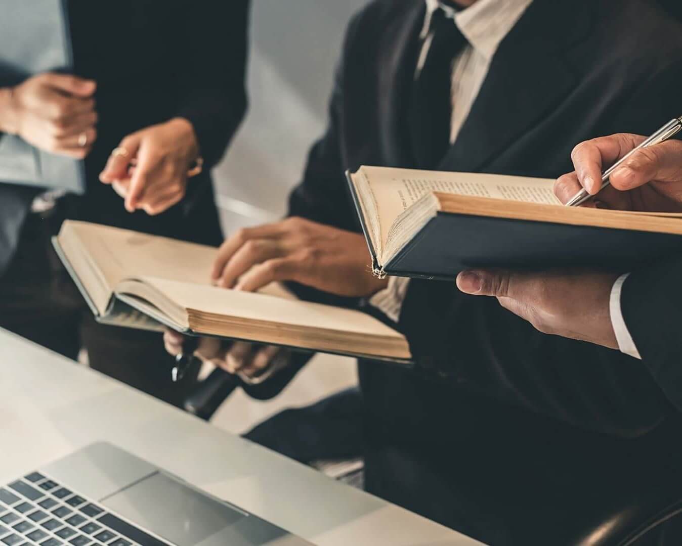 A lawyer providing federal employment law training to 2 men in suits as they review legal books.