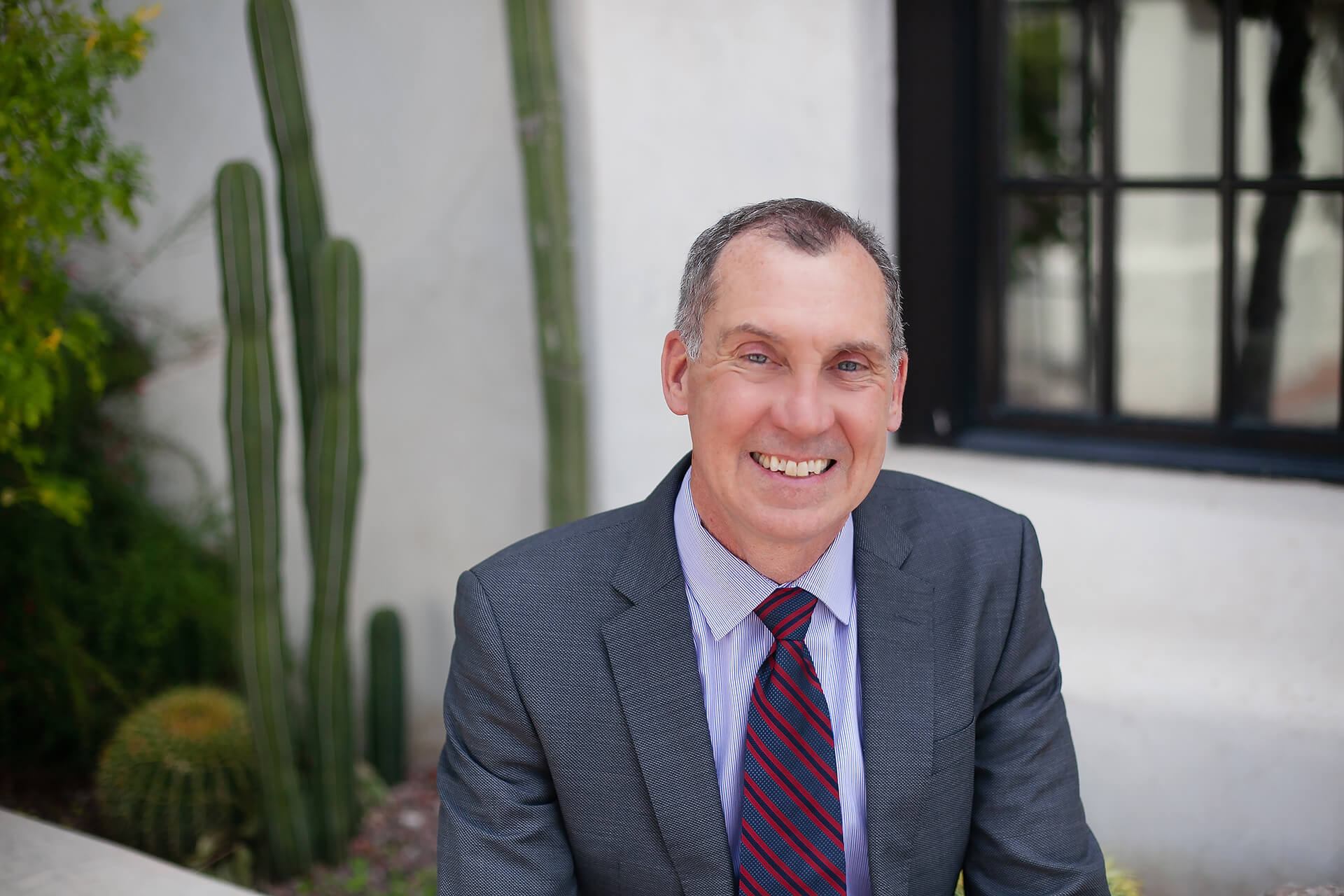Robert P. Erbe, a federal employee lawyer and merit systems protection board expert, outside of his office in Tucson, Arizona, wearing a grey suit and red tie.